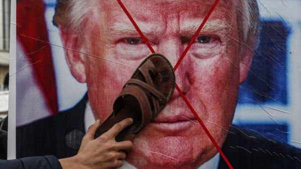 A Palestinian protester sticks his footwear on a poster depicting the face of US President Donald Trump during a demonstration against Trump's Middle East peace proposal in Khan Yunis in the southern Gaza Strip on February 3, 2020. SAID KHATIB / AFP