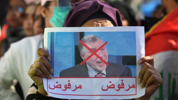 An Iraqi woman lifts a picture of the premier-designate Mohammad Allawi with the inscription "rejected", during an anti-government demonstration in the capital Baghdad's Tahrir square, on February 4, 2020. Anti-government demonstrators faced off against followers of the influential cleric Moqtada Sadr in protest squares across Iraq, a day after one demonstrator was killed in a clash between the two sides. Sadr backed the anti-government rallies when they erupted in October but has split with them by endorsi
