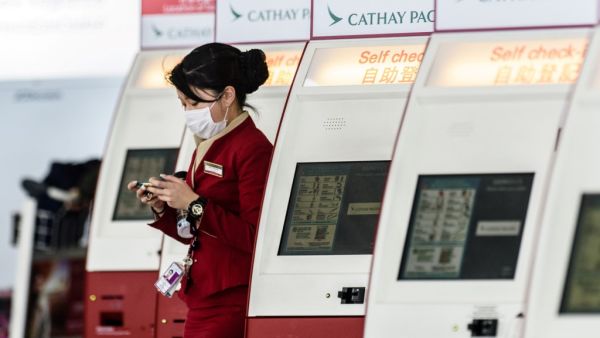 In this file photo taken on March 15, 2017, a mask-clad Cathay Pacific employee walks past a row of self check-in counters at the international airport in Hong Kong. AFP
