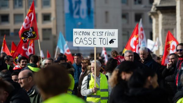 A protester wearing a yellow vest holds a sign reading "Macron, it's over, go away" as he takes part in a demonstration against the French government's plan to overhaul the country's retirement system in Marseille, southeastern France, on February 6, 2020. CLEMENT MAHOUDEAU / AFP