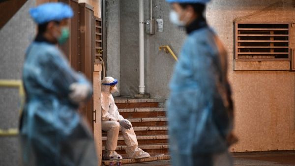 Medical personnels wearing protective suits stay near a block's entrance in the ground of a residential estate, in Hong Kong, early on February 11, 2020, after two people in the block were confirmed to have contracted the coronavirus according to local newspaper reports. Anthony WALLACE / AFP