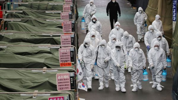 Market workers wearing protective gear spray disinfectant at a market in the southeastern city of Daegu on February 23, 2020 as a preventive measure after the COVID-19 coronavirus outbreak. AFP