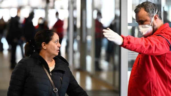 A member of the Fire safety and personal assistance (Service de securite incendie et d'assistance à personnes - SSIAP) gives indications to people at the train and bus station Lyon Perrache after marking a security zone, following the blockage of a bus coming from Milan due to suspected COVID-19 the novel coronavirus on board, in Lyon, on February 24, 2020. JEAN-PHILIPPE KSIAZEK / AFP