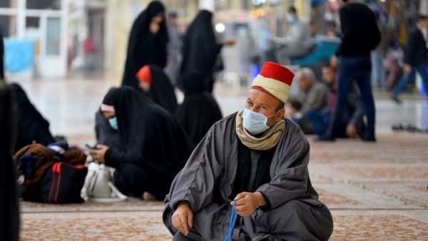 Worshippers wearing masks sit in the courtyard of the shrine of Imam Ali on February 25, 2020 in the holy Iraqi central city of Najaf, where the first case of coronavirus COVID-19 has been documented in Iraq. Iraq on February 24 confirmed its first novel coronavirus case in an elderly Iranian national in Najaf, according to health officials. A country with a dilapidated healthcare system, Iraq often hosts pilgrims and religious students from Iran, where at least a dozen people have died of the novel coronav