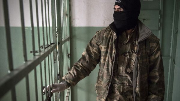 A member of the Syrian Democratic Forces (SDF) stands guard in a prison where men suspected to be afiliated with the Islamic State (IS) group are jailed in northeast Syria in the city of Hasakeh on October 26, 2019. Photo: FADEL SENNA / AFP