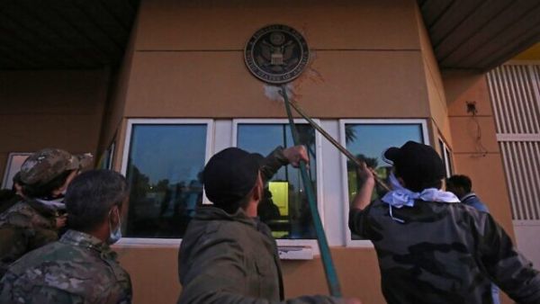 Iraqi supporters and members of the Popular Mobilization Forces paramilitary pull off a plaque from the entrance of the US embassy in Baghdad, Iraq, December 31, 2019. (Ahmad al-Rubaye/AFP)