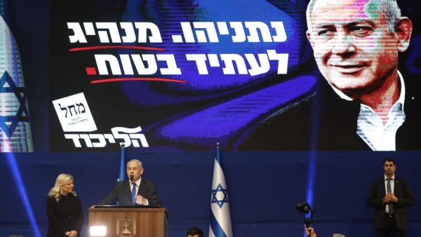Israeli Prime Minister Benjamin Netanyahu addresses supporters as his wife Sara stands by, at the Likud party campaign headquarters in the coastal city of Tel Aviv early on March 3, 2020, after polls officially closed. Netanyahu claimed "a giant victory" in elections on March 3, boasting that his right-wing Likud party had defied "all expectations" in the country's third vote in less than a year. After exit polls by three networks forecast that Likud and its allies were on track to win 59 parliamentary seat