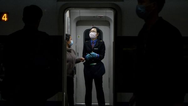 A train attendant wearing a facemask as a preventive measure against the spread of the COVID-19 coronavirus assists a passenger at the Changsha railway station in Changsha, the capital of Hunan province on March 5, 2020. More than 95,000 people have been infected and over 3,200 have died worldwide from the new coronavirus, which by on March 5 had reached some 80 countries and territories. Noel CELIS / AFP