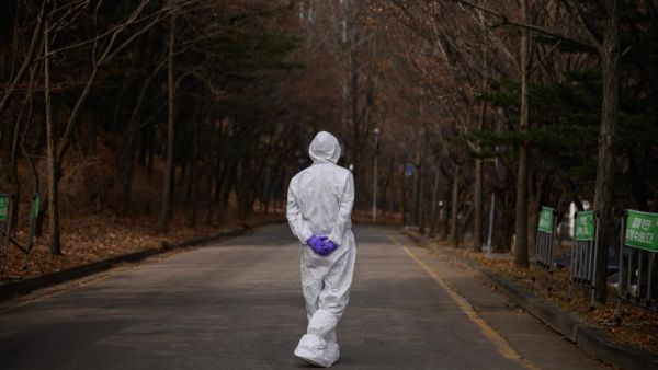 A health worker wearing a protective suit waits at a drive-through testing centre for the COVID-19 coronavirus in Seoul on March 7, 2020. South Korea has the biggest number of COVID-19 coronavirus cases outside China, with over 6,000 infections and 42 deaths, prompting the country to extend school breaks by three weeks. Ed JONES / AFP