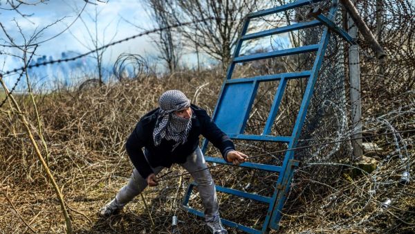 A migrant tries to breack fences near the Pazarkule crossing gate of the Turkey-Greece border on March 7, 2020 in the province of Edirne where makeshift camps have sprung up around the border as thousands of refugees have been encouraged by Turkey to leave for the European Union, in a bid to gain Western backing in Syria. AFP/File
