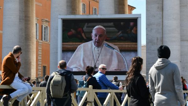People watch a screen live-broadcasting Pope Francis' Sunday Angelus prayer on St. Peter's Square at the Vatican on March 8, 2020, after millions of people were placed under forced quarantine in northern Italy as the government approved drastic measures in an attempt to halt the spread of the COVID-19 outbreak, caused by the novel coronavirus that is sweeping the globe. On top of the forced quarantine of 15 million people in vast areas of northern Italy until April 3, the government has also closed schools,