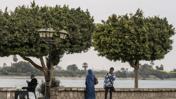 A picture take on March 11, 2020 shows an Egyptian police officer (L) sitting on the shore of the Nile river in Egypt's southern city of Luxor. Egyptian authorities said that 46 French and US tourists who had been quarantined on a coronavirus-hit Nile cruise boat have flown home. They were among dozens of foreign tourists and Egyptian crew who had been either confined to the vessel or hospitalised after an outbreak of the virus.  Khaled DESOUKI / AFP