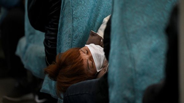 A passenger wearing a face mask naps inside a train as it passes through Wuhu in China's southeastern Anhui province on March 13, 2020. China reported just eight cases of the covid-19 coronavirus outbreak on March 13, with no new domestic infections outside the epicentre of Hubei province. Noel Celis / AFP