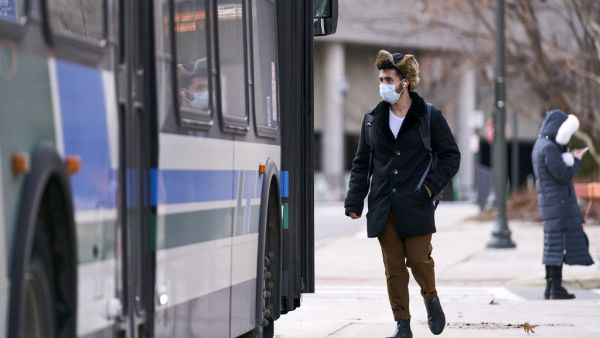 A man in a mask boards a bus on campus at Western University in London, Ontario on March 13, 2020 where in person classes have been suspended for the rest of the school year in favour of online instruction due to concerns over the the novel coronavirus, COVID-19. Geoff Robins / AFP