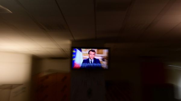 French President Emmanuel Macron is seen on a television screen as he speaks during a televised address to the nation on the outbreak of COVID-19, caused by the novel coronavirus, on March 16, 2020, in Paris. The French president addresses the nation, with many expecting him to unveil more strict home confinement rules in a bid to prevent the virus from spreading. France has closed down all schools, theatres, cinemas and a range of shops, with only those selling food and other essential items allowed to rem