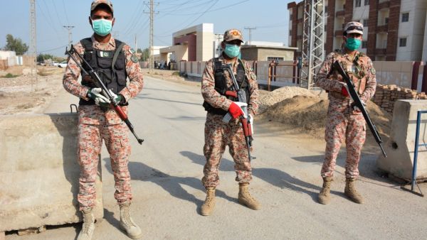 Soldiers wearing facemasks stand guard on road leading to a quarantine faciltity (R) for people returning from Iran via the Pakistan-Iran border town of Taftan to prevent the spread the COVID-19 coronavirus, in Sukkur in southern Sindh province on March 17, 2020. Shahid ALI / AFP