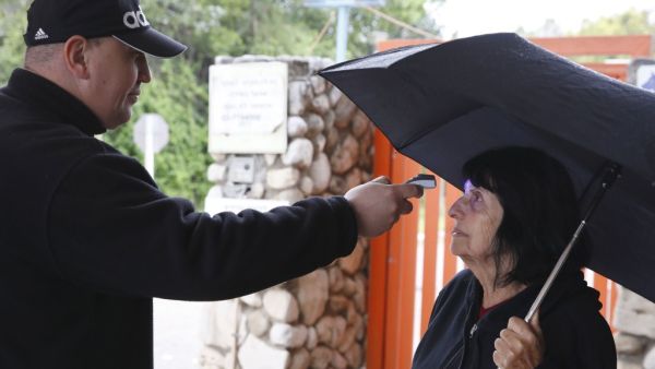 An Israeli security guard measures the temperature of a woman at the entrance to a retirement home in the Ramat Efal district of Ramat Gan in Israel, on March 17, 2020. JACK GUEZ / AFP