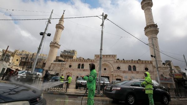 Amman municipality workers spray cars with sanitisers in the Jordanian capital on March 18, 2020 amidst measures to fight the spread of the coronavirus COVID-19. Khalil MAZRAAWI / AFP
