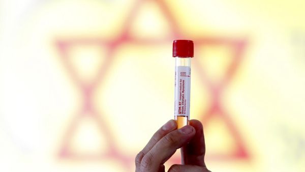 An Israeli medical personnel displays a sample taken from a driver at the Israeli Magen David Adom (MDA) national emergency service drive through complex for COVID-19 testing in Hayarkon Park's Rokach blvd parking lot in the coastal city of Tel Aviv on March 20, 2020. AFP