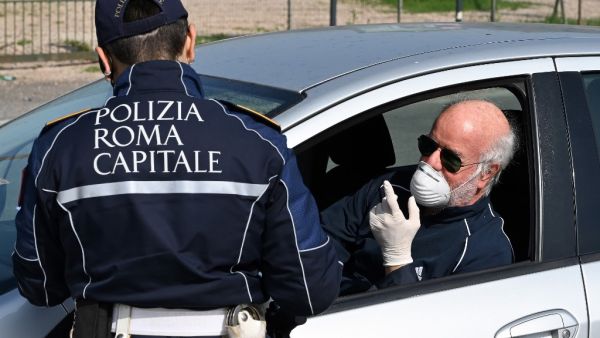 A member of the Rome Local Police checks the documents and the self-declaration of a motorist, wearing a facemask for protective reasons, on the Via Pontina, in Rome, on March 21, 2020, during the country's lockdown aimed at stopping the spread of the COVID-19. AFP/File