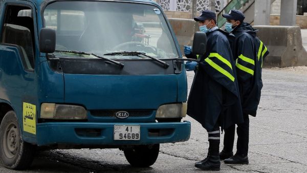 Policemen speak to a truck driver at a checkpoint in the Jordanian capital Amman during a nationawide curfew imposed by the authorities in order to control the spread of the novel coronavirus, on March 21, 2020. Khalil MAZRAAWI / AFP