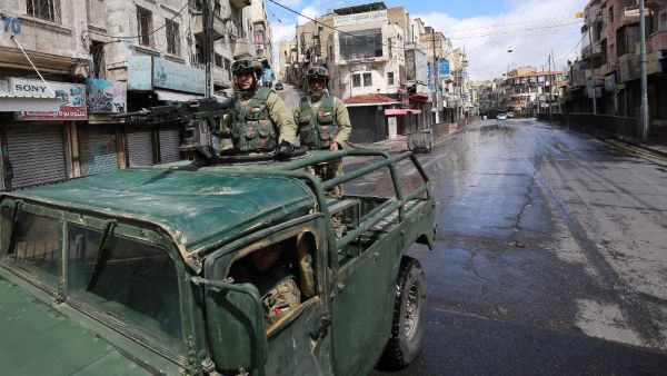 Soldiers from the Jordanian army patrol atop a military vehicle on a street in capital Amman during a nationawide curfew imposed by the authorities in order to control the spread of the novel coronavirus, on March 21, 2020. Khalil MAZRAAWI / AFP