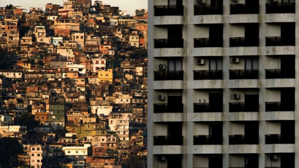 This file picture taken on September 27, 2017 shows a view of the Rocinha (L) favela seen behind a building of Sao Conrado neighbourhood, one of the richest areas of Rio de Janeiro. As the spread of the new coronavirus COVID-19 accelerates in Brazil, the poor populations crammed into the often unsanitary homes and precarious health services in the favelas, are on great alert. Mauro PIMENTEL / AFP