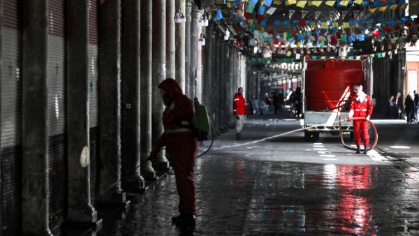 A Syrian Red Crescent member sprays disinfectant along an alley of the historic Hamidiyah souk (market) in the old city of Syria's capital Damascus on March 22, 2020, as part of efforts against the COVID-19 coronavirus pandemic. LOUAI BESHARA / AFP