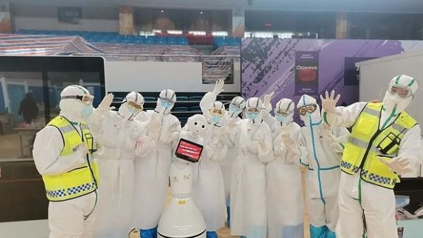 A group of medical workers are pictured with one of the robots in Wuchang field hospital (Dailymail)