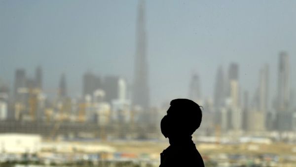 A man wearing a protective mask stands at a racetrack overlooking Dubai following the UAE's decision to postpone the upcoming Dubai Horse Racing amid the COVID-19 coronavirus pandemic, on March 23, 2020 in Dubai. KARIM SAHIB / AFP