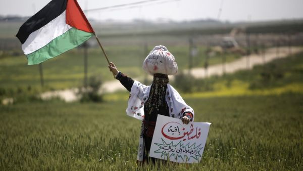 A Palestinian woman waves her national flag during an event marking Land Day near the Israel-Gaza border as mass rallies planned to commemorate the event were cancelled amid concerns about the spread of coronavirus disease (COVID-19), east of Gaza City, on March 30, 2020. MOHAMMED ABED / AFP