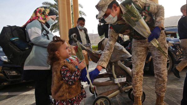A Jordanian soldier greets people with flowers as they leave a Dead Sea resort where they have been quarantined for 14 days, approximately 60 kilometres sout of the Jordanian capital Amman on March 30, 2020. AFP