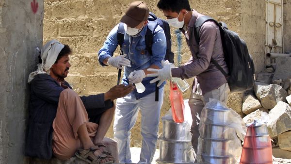 Yemeni volunteers spray disinfectant on the hands of a man in the one of Sanaa's impoverished neighbourhoods, on March 30, 2020, amid concerns of a coronavirus outbreak. MOHAMMED HUWAIS / AFP