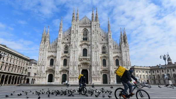Two cyclists working for the food delivery service Glovo ride their bike across a deserted Piazza Duomo in Milan, on March 31, 2020, during the country's lockdown aimed at curbing the spread of the COVID-19 infection, caused by the novel coronavirus. Piero Cruciatti / AFP