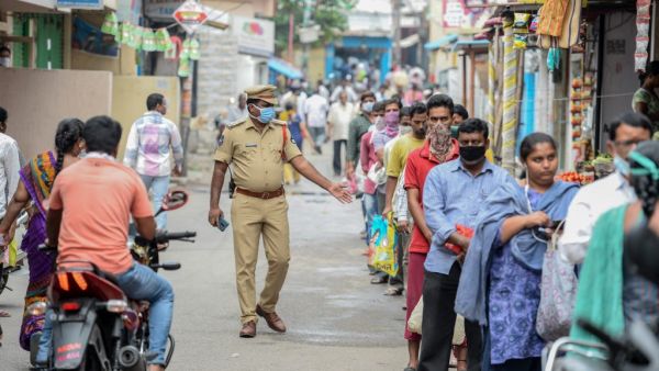 A policeman (C) patrols as people queue to receive free rice distributed at a government civil supply store during a government-imposed nationwide lockdown as a preventive measure against the COVID-19 coronavirus, in Hyderabad on April 1, 2020. NOAH SEELAM / AFP