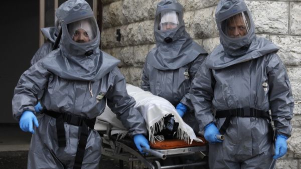 Workers at Israel's religious burial society Chevra Kadisha wearing protective equipment, carry the body of a patient who died from complications of Coronavirus (COVID-19) infection, at the Shamgar Funeral Home in Jerusalem, on April 1, 2020. Ahmad GHARABLI / AFP