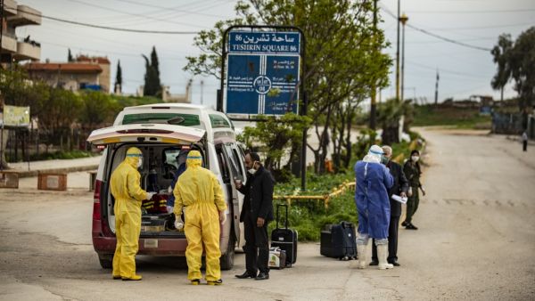 Members of the Kurdish Red Crescent check passengers who were stranded in Damascus upon their arrival at the Qamishli airport in Syria's northeastern Hasakeh province on April 5, 2020. Passengers will undergo a two-week quarantine at a designated centre in the Kurdish-majority city of Qamishli. DELIL SOULEIMAN / AFP