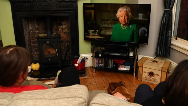 A picture shows a family in Birkenhead, northwest England on April 5, 2020 watching Britain's Queen Elizabeth II deliver a special address to the UK and Commonwealth recorded at Windsor Castle in relation to the coronavirus outbreak. Queen Elizabeth II urgeed people to rise to the challenge posed by the coronavirus outbreak, in a rare special address to Britain and Commonwealth nations on Sunday. PAUL ELLIS / AFP