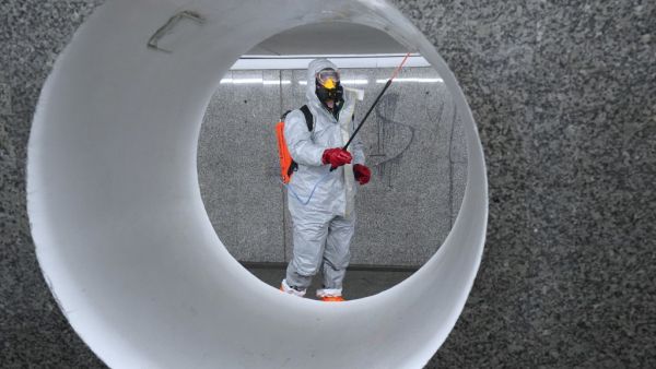 Workers wearing protective suits spray disinfectant at the Centrum subway station in Warsaw on April 6, 2020. JANEK SKARZYNSKI / AFP