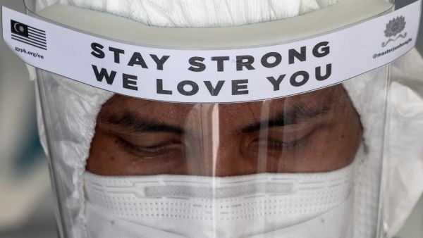 A health worker wearing a protective suit prepares to enter two apartment buildings in Kuala Lumpur on April 8, 2020, after they were cordoned off due to a number of cases of individuals with COVID-19 novel coronavirus at the premises. Mohd RASFAN / AFP