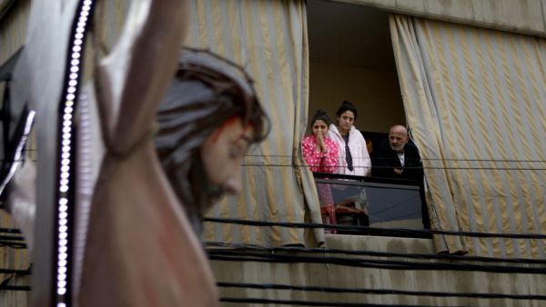 Lebanese Christians watch a crucifix shrine car procession on Good Friday, from their balcony in the dominantly Christian suburb of Dekwaneh, east of the capital Beirut, on April 10, 2020, during the novel coronavirus pandemic crisis. PATRICK BAZ / AFP