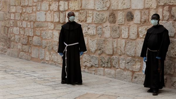 Franciscan friars wearing protective masks amid the COVID-19 pandemic stand in the yard of the Church of the Holy Sepulchre in Jerusalem's Old City, on April 9, 2020. All cultural sites in the Holy Land are shuttered, regardless of their religious affiliation, as authorities seek to forestall the spread of the deadly respiratory disease, which will prevent Christians from congregating for the Easter service, this coming Sunday for Catholic worshippers, then a week later on April 19 for Orthodox Easter. GALI