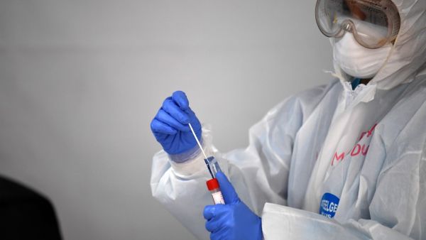 A health worker places a swab in a tube asfter testing a foreign worker for the novel coronavirus at a testing centre in the Naif area of the Gulf Emirate of Dubai, on April 15, 2020. KARIM SAHIB / AFP