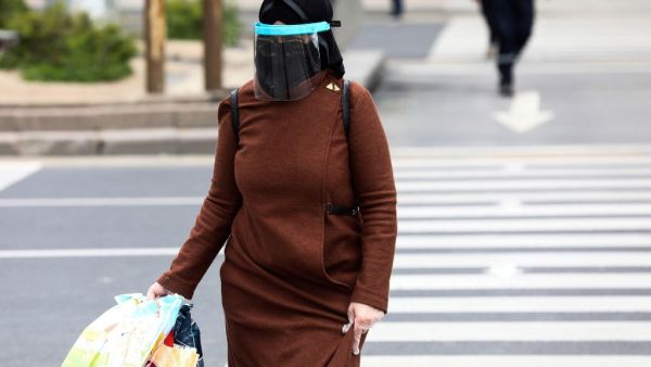 A woman wearing a face-shield and plastic gloves for protective measures crosses the streets as the spread of the COVID-19, the novel coronavirus continues in Ankara, on April 16, 2020. Adem ALTAN / AFP