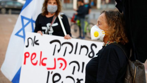 Israeli women wearing a face masks take part in a "Black Flag" demonstration, to protest against Prime Minister Benjamin Netanyahu and anti-democratic measures to contain the novel coronavirus outbreak, at Rabin Square in the coastal city of Tel Aviv, on April 19, 2020. JACK GUEZ / AFP