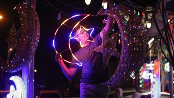 A Palestinian youth hangs decorative lights at a shop in east Jerusalem on April 21, 2020, as Muslims prepare for the start of the holy fasting month of Ramadan. Ahmad GHARABLI / AFP`