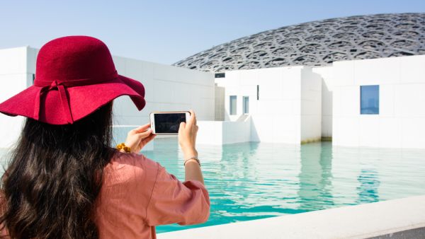 Female tourist taking picture of Louvre Abu Dhabi building. (Shutterstock/ File Photo)