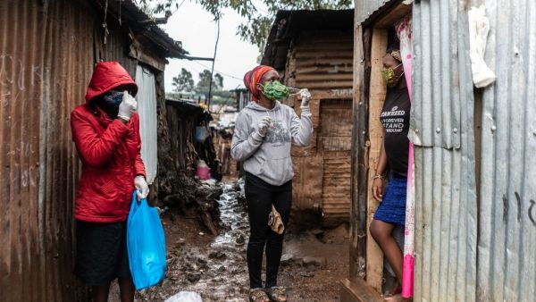 Florence Akiuor (2nd L) of Coalition for grassroots human rights defenders Kenya (CGHRD'S Kenya) explains how to use a mask during their food distribution. (AFP)