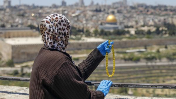 A Palestinian woman holds prayer beads after performing the second Friday prayer of the Muslim holy month of Ramadan at the Mount of Olives, as she looks at the Old City of Jerusalem and the closed-down Aqsa Mosque compound, on May 1, 2020, amid heightened security and social distancing measures due to the COVID-19 pandemic. AHMAD GHARABLI / AFP