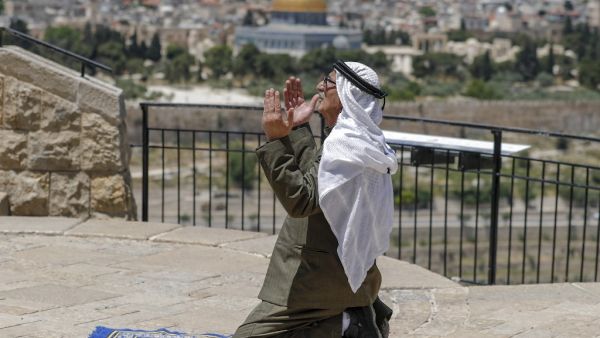 An elderly Palestinian man performs the Friday prayer during the Muslim holy month of Ramadan, at the Mount of Olives with a backdrop of the Old City of Jerusalem and the closed al-Aqsa Mosque compound, on May 8, 2020, amid the novel coronavirus pandemic crisis. AHMAD GHARABLI / AFP